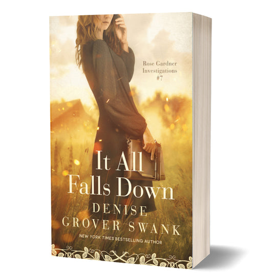 Book cover of 'It All Falls Down' by Denise Grover Swank with a woman holding a book in a field.