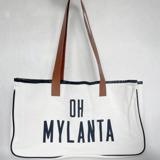 A white canvas tote bag with brown PU leather handles and black trim, featuring the text 'OH MYLANTA' in bold black letters.